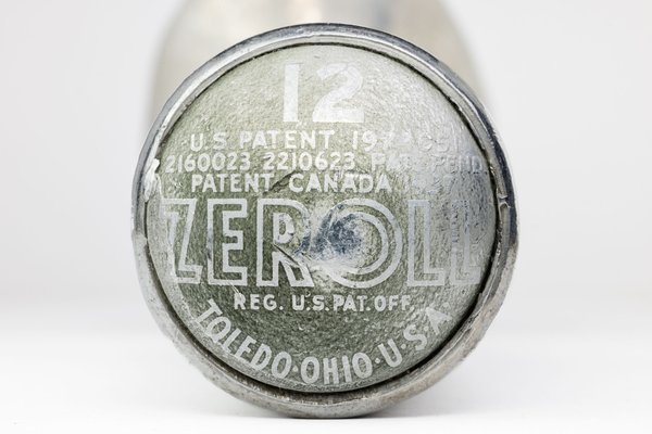 A round, light green and silver end of an ice cream scoop with worn-off text. The text includes "ZEROLL," "TOLEDO, OHIO, U.S.A.," and patent numbers. The number "12" is prominently displayed in white. The surface shows signs of age and wear, with scratches and faded areas.