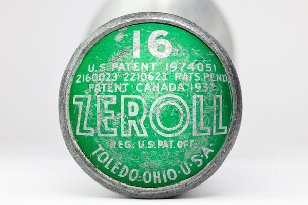 A round, green and silver end of an ice cream scoop with worn-off text. The text includes "ZEROLL," "TOLEDO, OHIO, U.S.A.," and patent numbers. The number "16" is prominently displayed in white. The surface shows signs of age and wear, with scratches and faded areas.